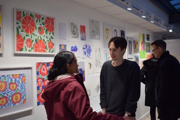 Art Club Committee member talks to visitor at exhibition