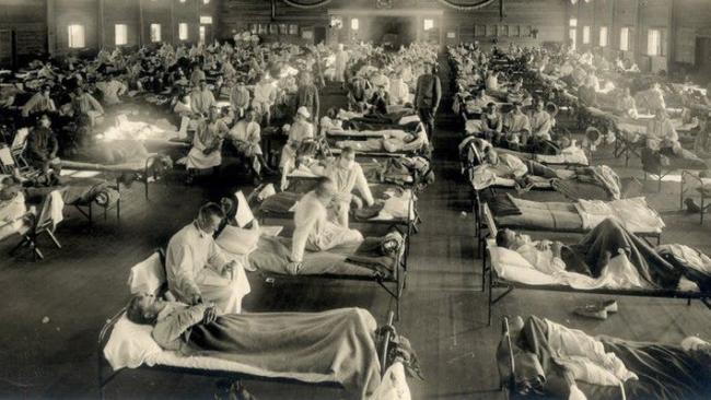 Image of A historic mass hospital ward with patients being tended by medical staff